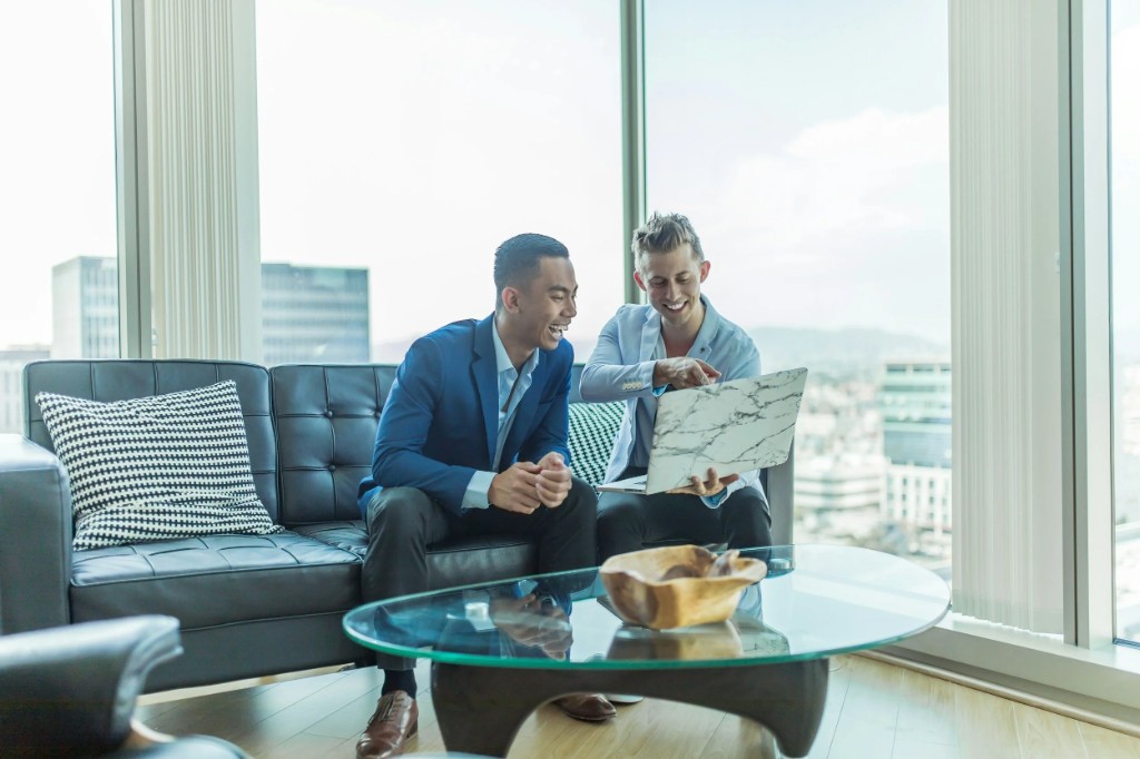 Two professionals collaborating while reviewing financial work on a laptop.